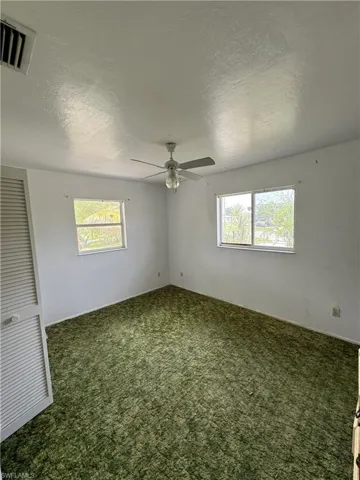 Spare room featuring carpet floors, a textured ceiling, and ceiling fan