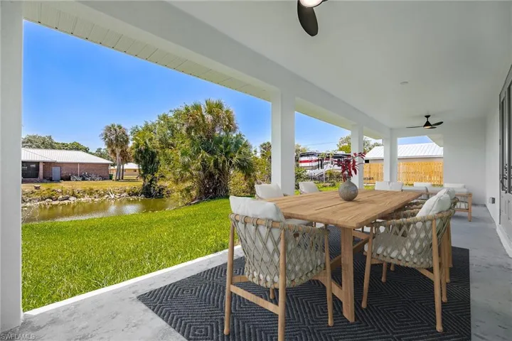 View of patio with outdoor dining space, ceiling fan, and a water view