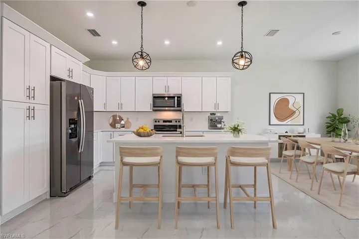 Kitchen featuring recessed lighting, decorative backsplash, stainless steel appliances, visible vents, and light countertops