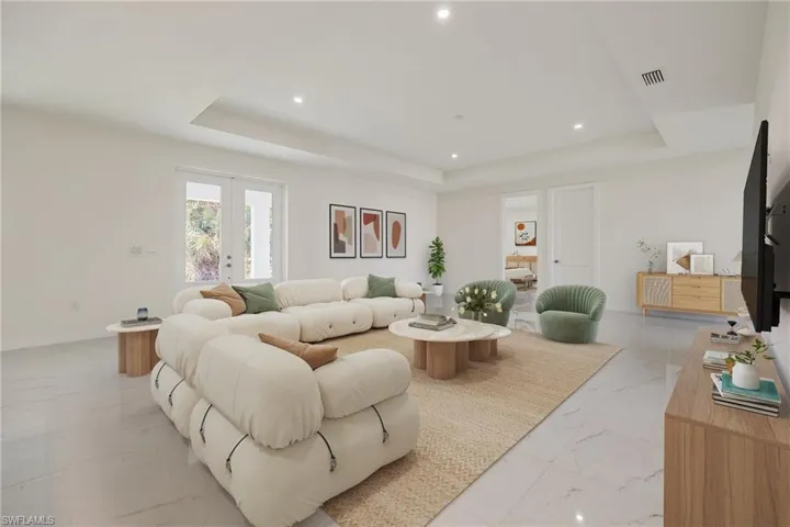 Living area featuring recessed lighting, a raised ceiling, marble finish floor, visible vents, and baseboards