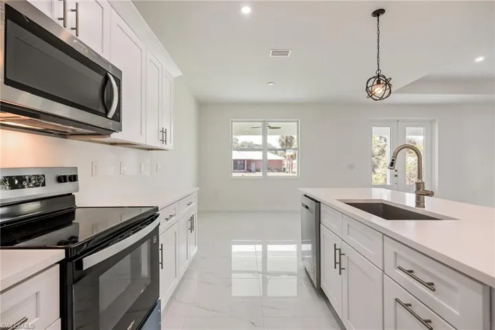 Kitchen featuring recessed lighting, a sink, stainless steel appliances, marble finish floor, and light countertops