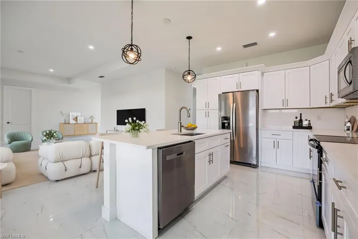 Kitchen with a sink, appliances with stainless steel finishes, open floor plan, recessed lighting, and marble finish floor