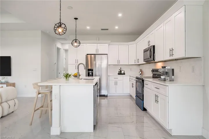 Kitchen featuring recessed lighting, a sink, stainless steel appliances, marble finish floor, and backsplash