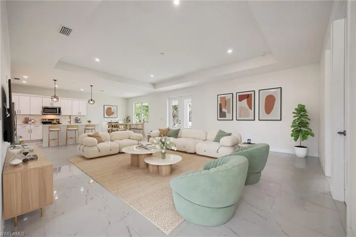Living area with recessed lighting, a raised ceiling, marble finish floor, visible vents, and baseboards