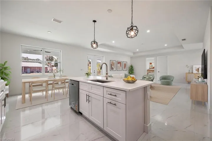 Kitchen with a sink, a tray ceiling, marble finish floor, visible vents, and stainless steel dishwasher