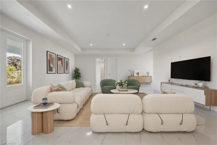 Living room with recessed lighting, marble finish floor, visible vents, and a raised ceiling