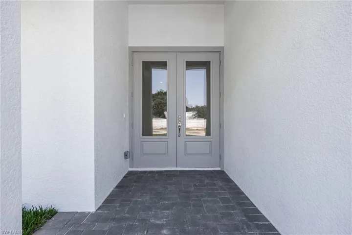 View of exterior entry featuring stucco siding and french doors