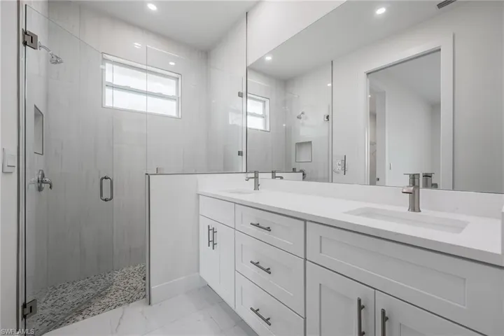 Bathroom featuring double vanity, a stall shower, and a sink