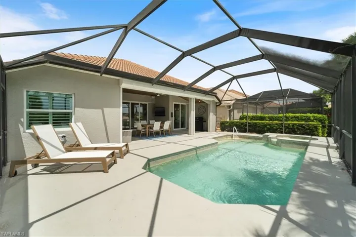 View of pool with a patio, a pool with connected hot tub, outdoor dining space, and a lanai
