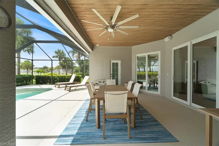View of patio featuring a ceiling fan, an outdoor pool, outdoor dining space, and glass enclosure