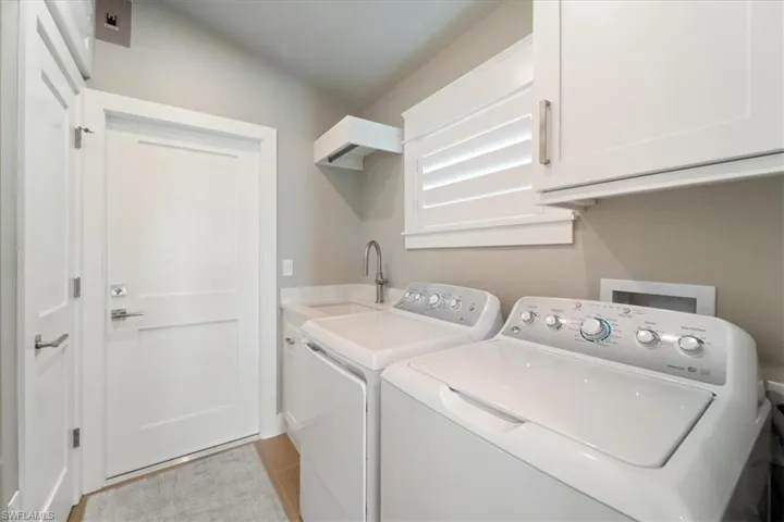 Laundry area with cabinet space, separate washer and dryer, and light tile patterned flooring