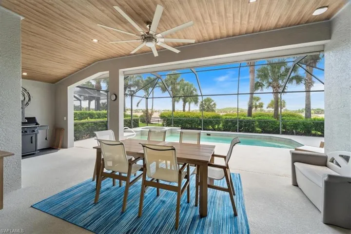 View of patio featuring a ceiling fan, glass enclosure, outdoor dining space, and an outdoor pool