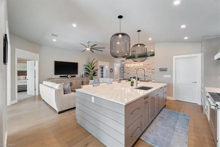 Kitchen with an island with sink, ceiling fan, open floor plan, stainless steel stove, and recessed lighting