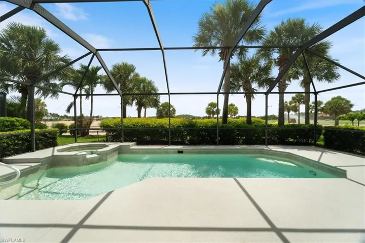 View of swimming pool featuring a patio, glass enclosure, and a pool with connected hot tub