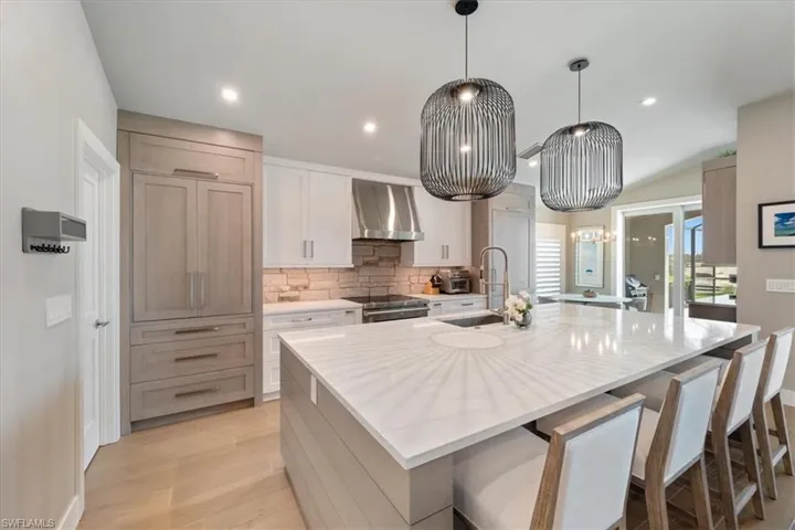 Kitchen with wall chimney range hood, a large island, decorative backsplash, light wood finished floors, and recessed lighting