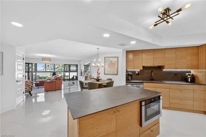 Kitchen with modern cabinets, open floor plan, hanging lights, backsplash, and stainless steel appliances