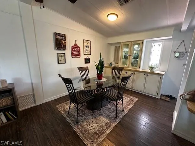 Dining room featuring a textured ceiling, dark wood-type flooring, and lofted ceiling