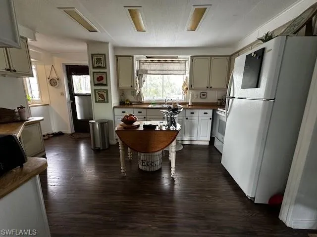 Kitchen with sink, a textured ceiling, white appliances, and dark wood-type flooring