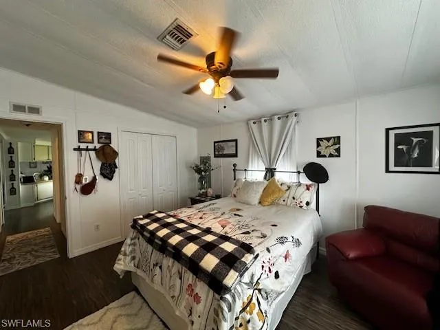 Bedroom featuring a textured ceiling, lofted ceiling, dark hardwood / wood-style flooring, a closet, and ceiling fan
