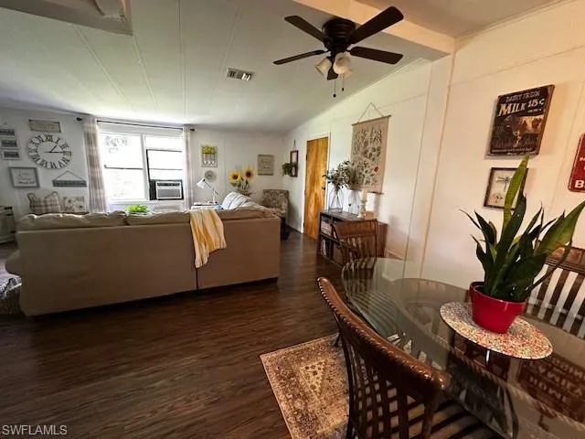 Living room featuring lofted ceiling, ceiling fan, and dark hardwood / wood-style flooring