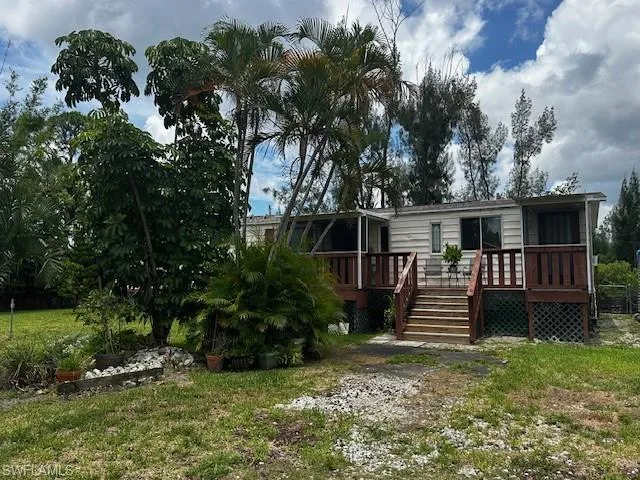 Rear view of property featuring a deck and a lawn