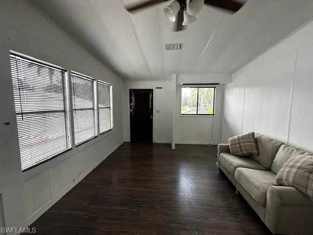 Living room with a textured ceiling, ceiling fan, and dark hardwood / wood-style floors