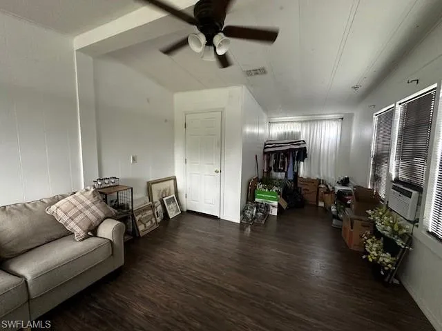 Living room with ceiling fan and dark hardwood / wood-style flooring