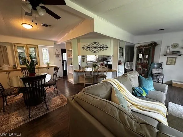 Living room featuring dark wood-type flooring, ceiling fan, french doors, and lofted ceiling