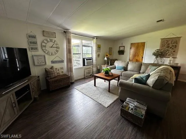 Living room with dark hardwood / wood-style flooring and lofted ceiling
