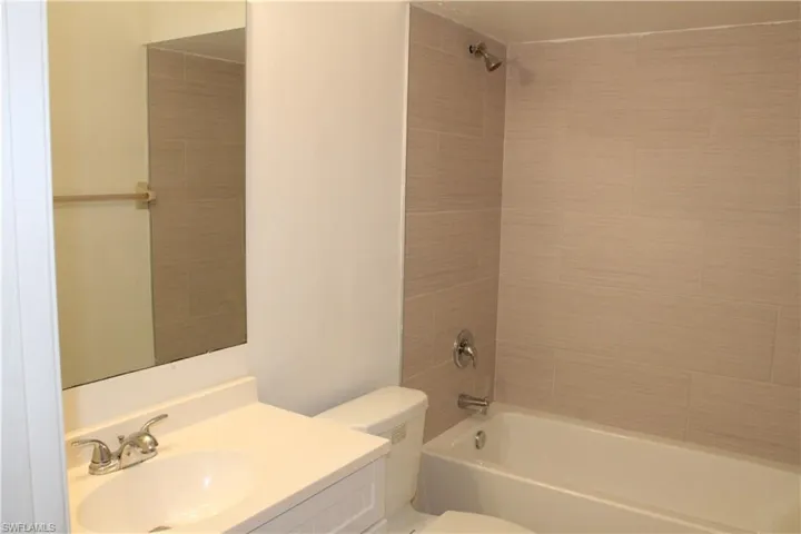 Full bathroom featuring tiled shower / bath combo, toilet, and vanity