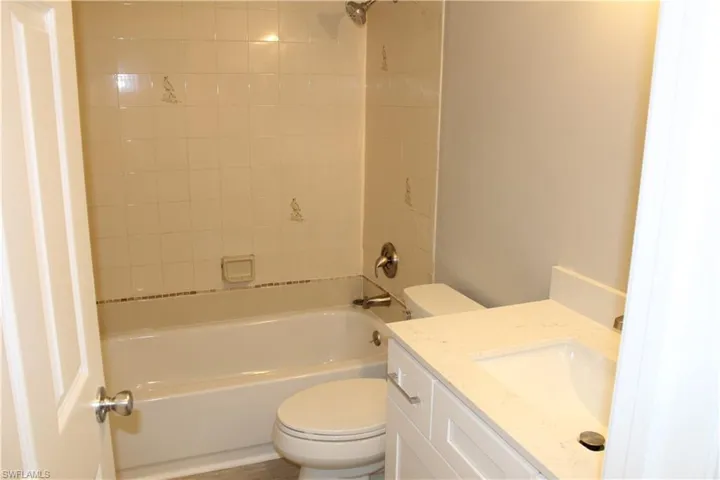 Full bathroom with tiled shower / bath, toilet, and vanity