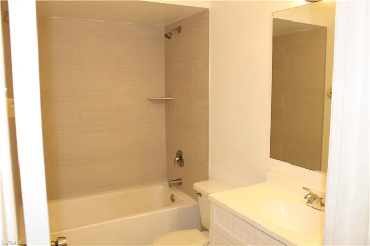 Full bathroom with tiled shower / bath, toilet, and vanity