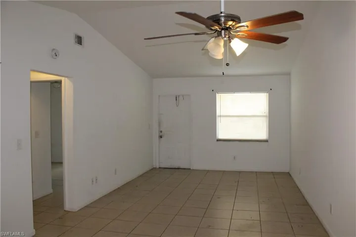 Unfurnished room featuring ceiling fan, vaulted ceiling, and light tile patterned floors