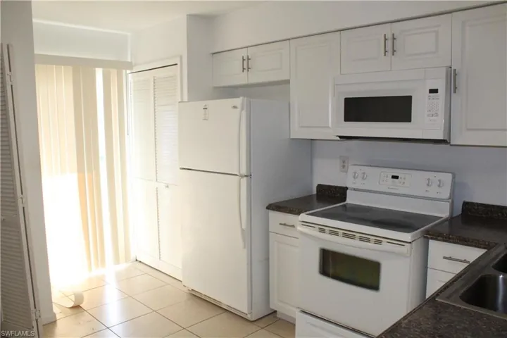 Kitchen featuring white appliances, white cabinets, and light tile patterned floors