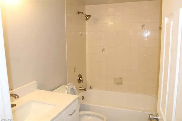 Full bathroom with toilet, tiled shower / bath combo, and vanity