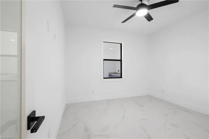 Empty room featuring light marble finish floors and a ceiling fan