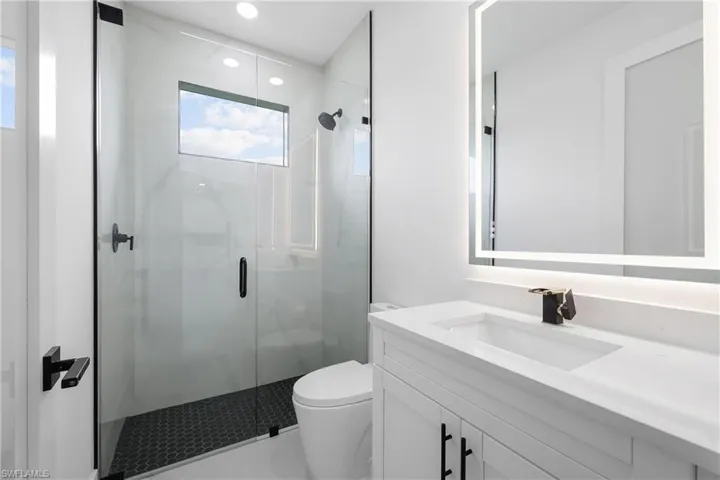 Full bathroom with vanity, a marble finish shower, and recessed lighting
