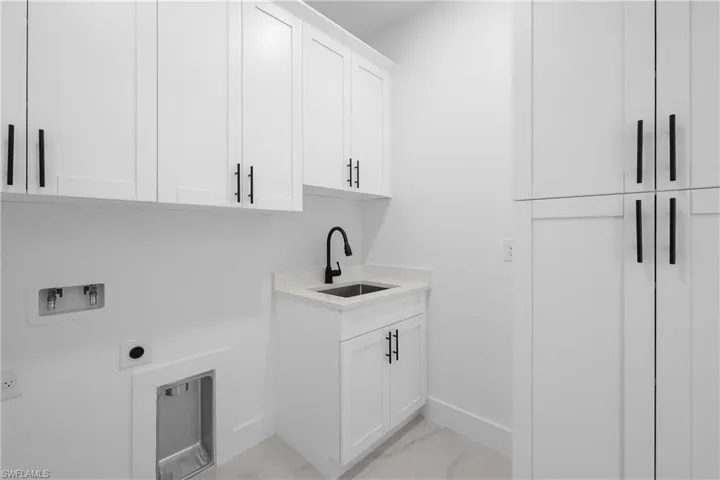 Washroom featuring cabinet space, light marble finish floors, hookup for an electric dryer, and washer hookup
