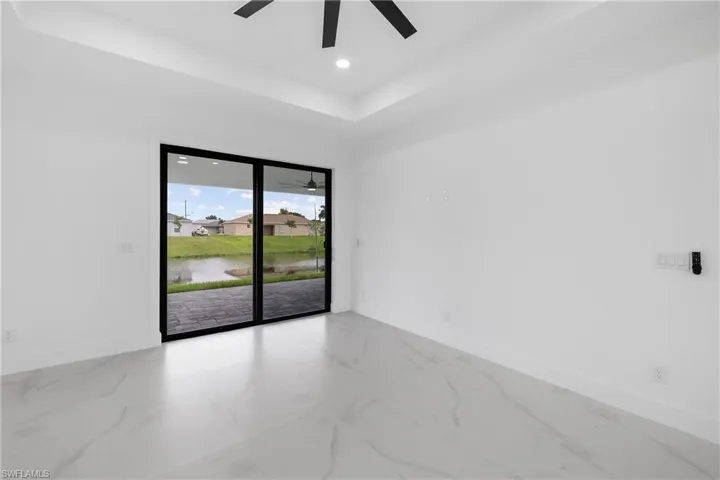 Empty room featuring a water view, marble look tile flooring, recessed lighting, a raised ceiling, and ceiling fan