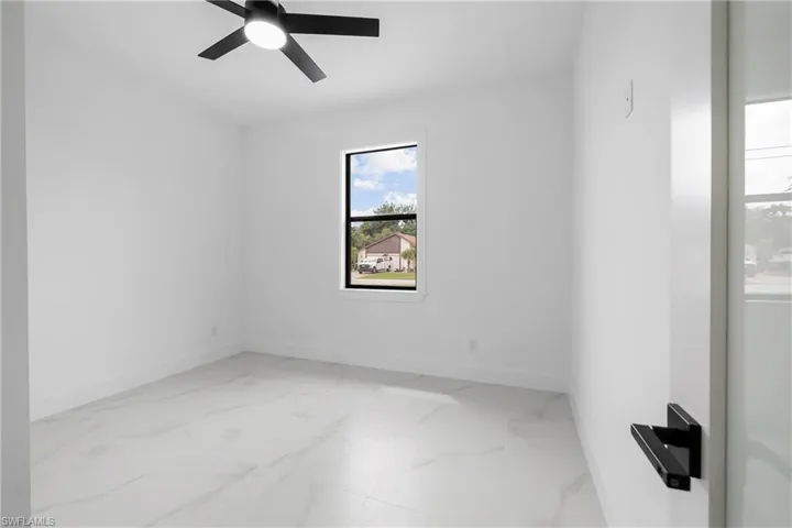 Unfurnished room with light marble finish floors and ceiling fan