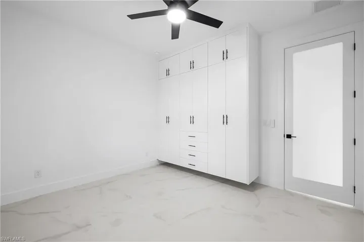 Unfurnished bedroom featuring light marble finish flooring, a closet, and a ceiling fan