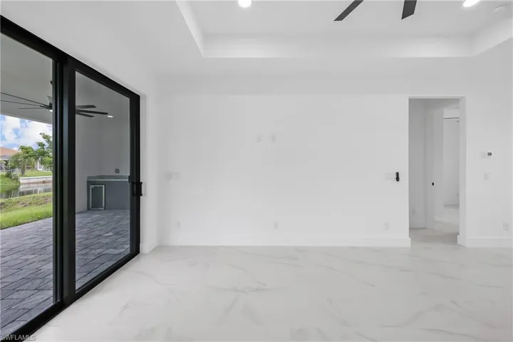 Spare room with a ceiling fan, light marble finish flooring, recessed lighting, and a raised ceiling