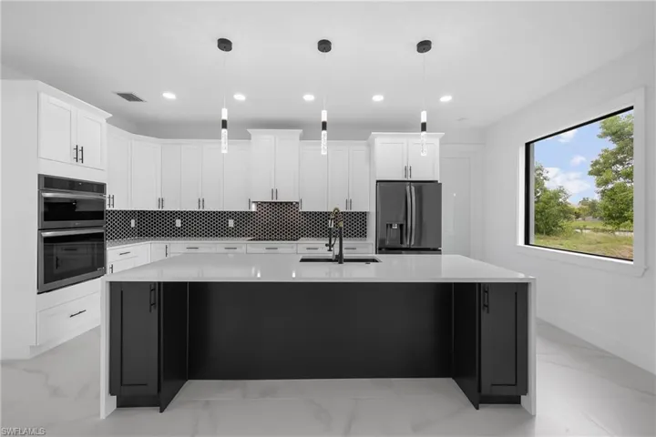 Kitchen with backsplash, light marble finish floors, light stone counters, decorative light fixtures, and recessed lighting