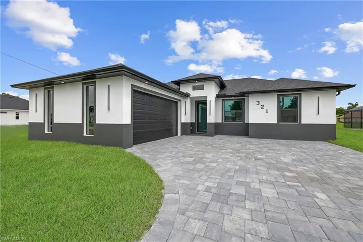 Prairie-style house featuring stucco siding, decorative driveway, and an attached garage