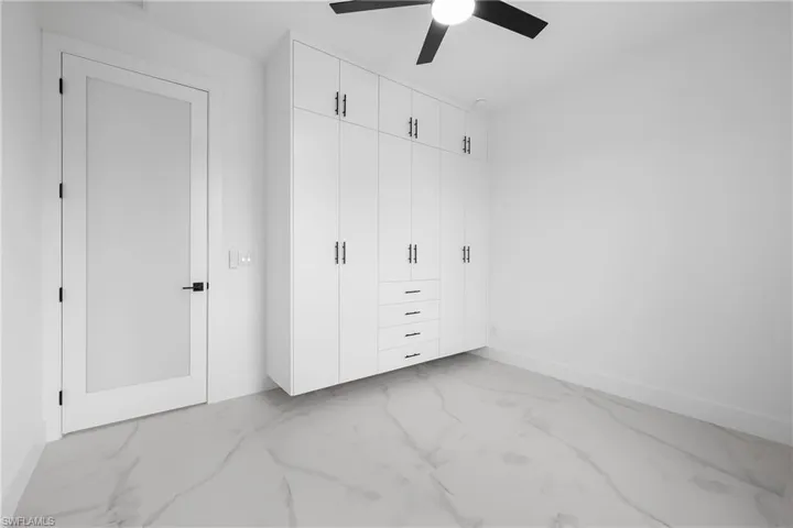 Unfurnished bedroom with a closet, light marble finish flooring, and a ceiling fan