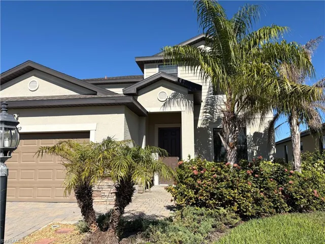 Property entrance featuring an attached garage, stucco siding, and decorative driveway