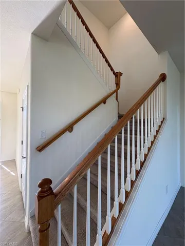Staircase with baseboards and tile patterned floors