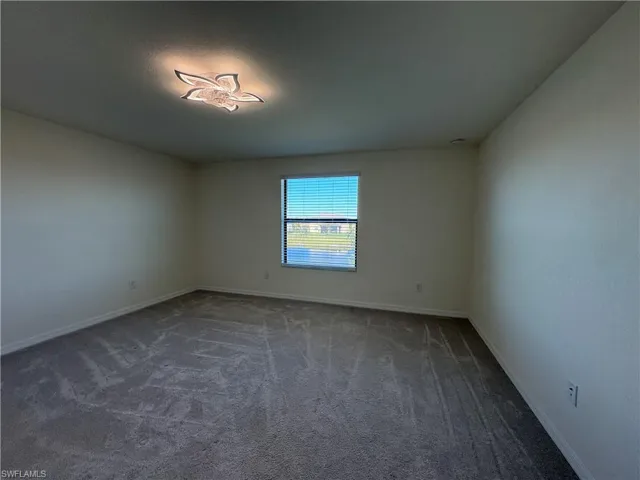 Empty room featuring dark carpet and baseboards
