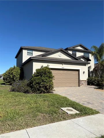View of front facade featuring decorative driveway, stucco siding, a front lawn, and an attached garage