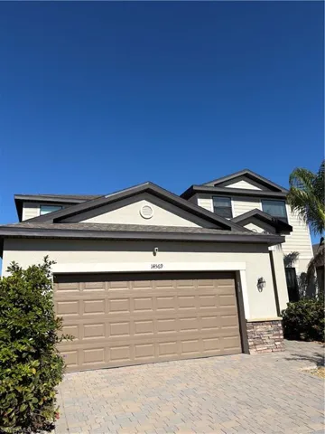 View of front of home with stucco siding, decorative driveway, and stone siding